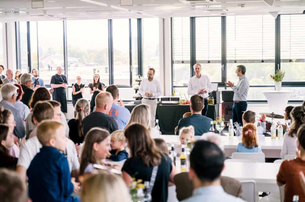 Geschäftstreffen mit Präsentation vor großem Publikum in hellen Raum.