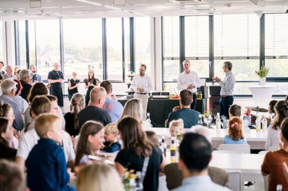 Geschäftstreffen mit Präsentation vor großem Publikum in hellen Raum.